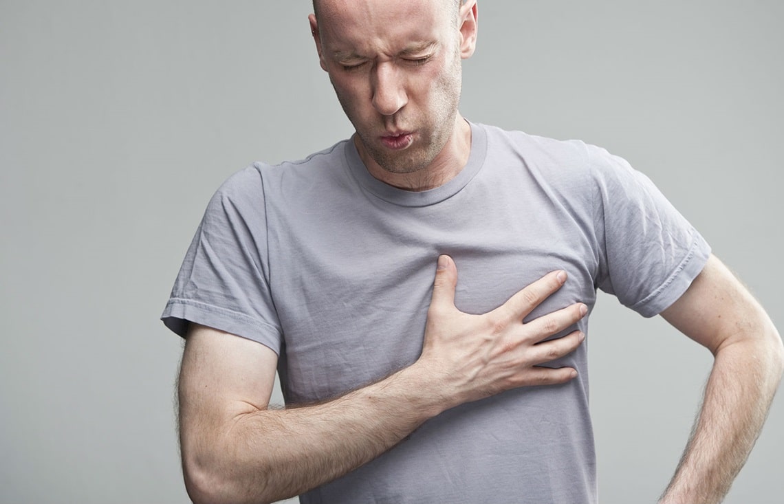 person clutching thier chest & how jaw pain can be a sign of a heart attack